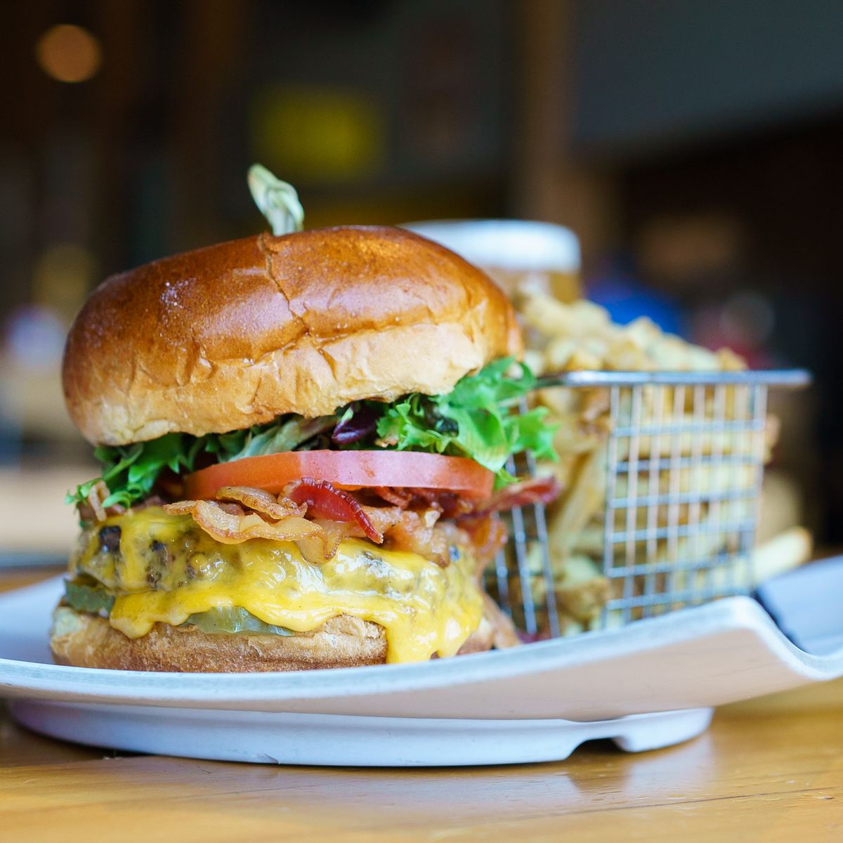 A bacon cheeseburger in a basket with fries